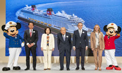 Executives from Disney and the Oriental Land Co. are flanked by Mickey and Minnie Mouse at an event to share details of their agreement to bring Disney sailings to Japan in 2029. Behind them is a rendering of the ship that will be used for those initial sailings.