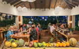 Guests gather at Buccan's communal dining tables for a family-style feast featuring local "Vincy" cuisine.