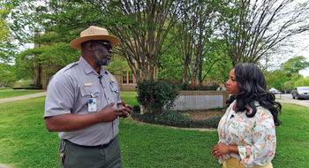 Denella Ri’chard discusses the Little Rock Nine with Ranger Randy during her visit to the Little Rock Central High School National Historic Site in Arkansas. The site was among those featured in her Black History Month TV special.